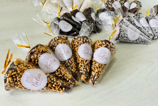 Cones embalados com cobertura crocante e etiqueta Bolin Doces, ao lado de cones de chocolate e de granulado.