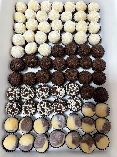 Bandeja de docinhos em forminhas pretas: de coco, de chocolate, de granulado e bicolores.